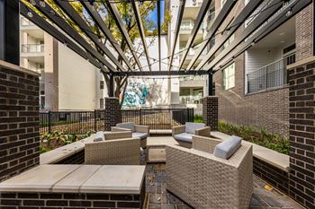 an outdoor patio with chairs and tables and a glass ceiling at The Monroe Apartments, Austin, TX, 78741